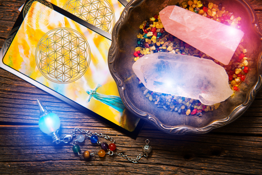 A yellow tarot card is seen with a bowl of glowing crystals.